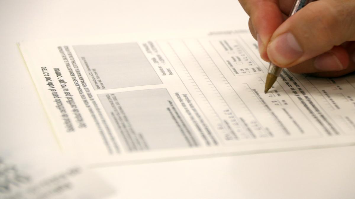 Un votant omple la sol·licitud de vot per correu a l'oficina de Correus de Gran de Gràcia de Barcelona