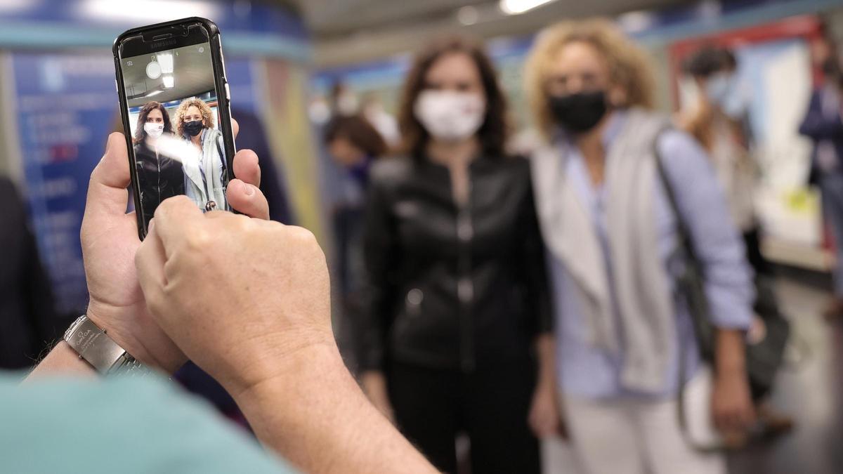 La presidenta de la Comunidad de Madrid, Isabel Díaz Ayuso (i), se hace una fotografía con una seguidora.