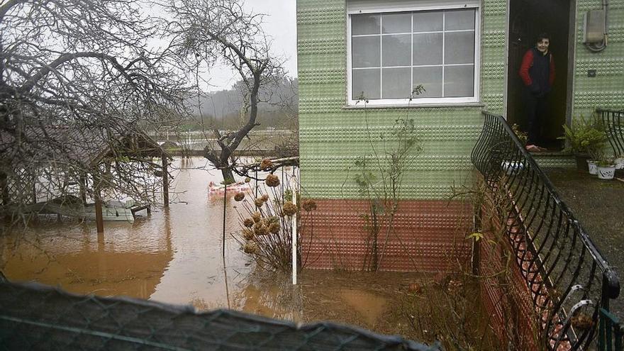 Albina Pérez, a la puerta de su casa, anegada por la crecida del río Nalón.