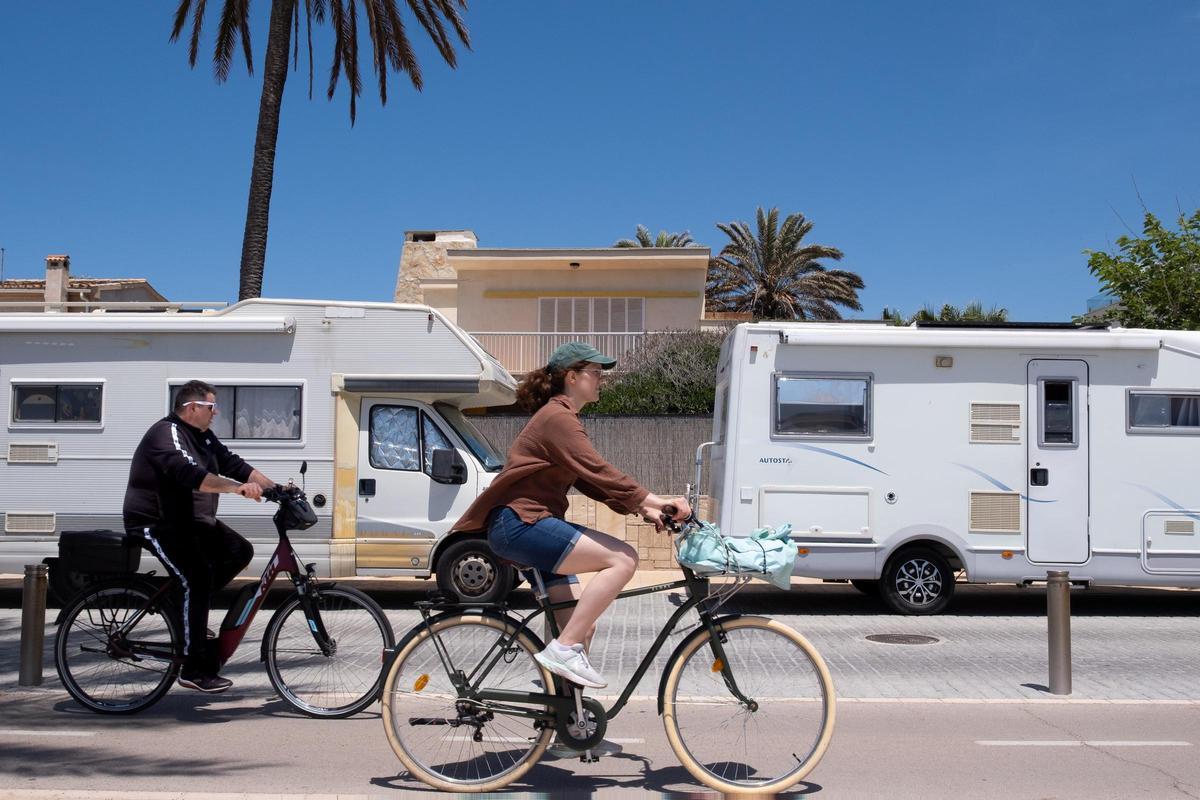 Dos ciclistas pasan por delante de dos caravanas aparcadas en primera línea de Ciudad Jardín