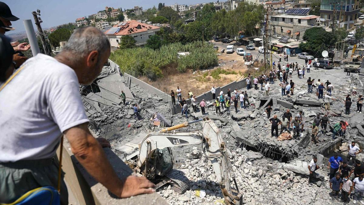 Un hombre contempla las labores de los equipos de emergencia tras el bombardeo israelí sobre la localidad libanesa de Deir el Zahrani.