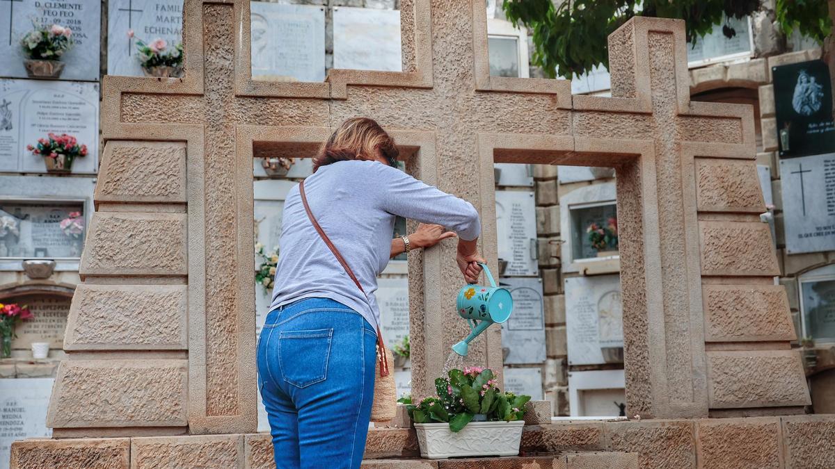 Una mujer riega las plantas en un cementerio del Archipiélago.