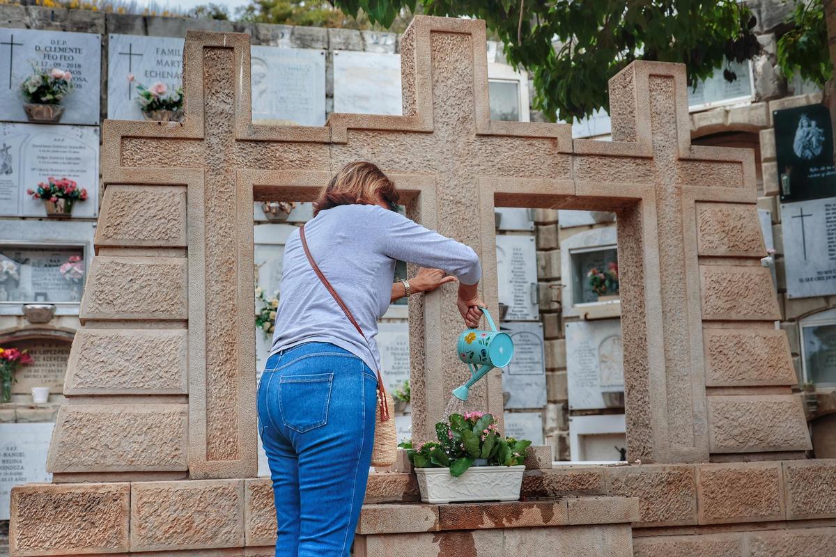 Una mujer riega las plantas en un cementerio del Archipiélago.