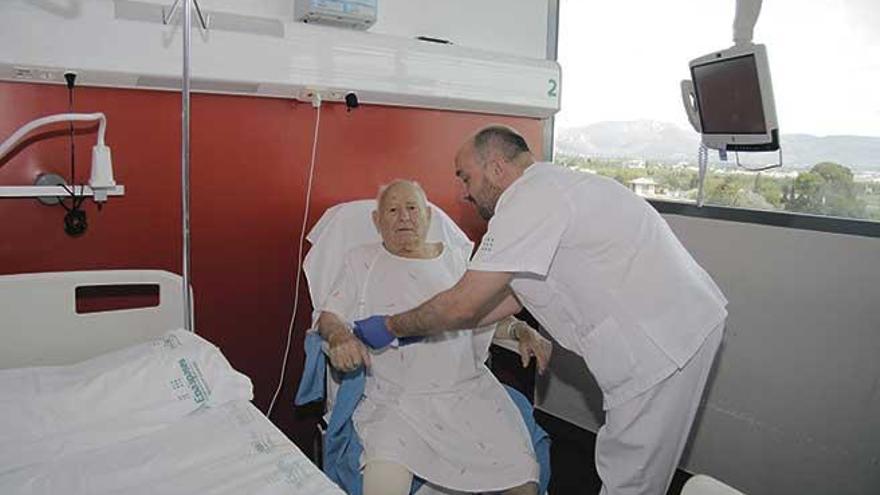 Un paciente anciano frágil, atendido por un sanitario en una habitación del hospital de Son Espases.