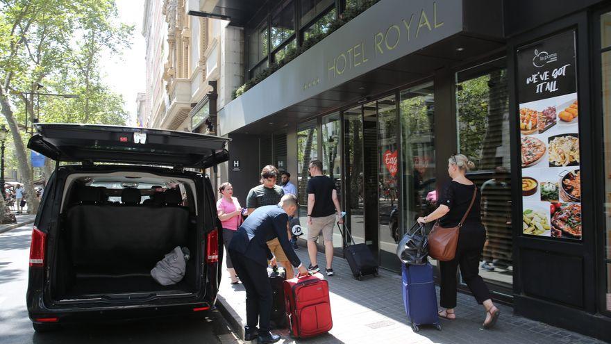 El conductor de una VTC descarga las maletas de unos turistas.