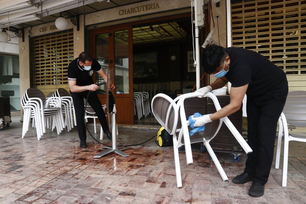 Imágenes de una lluviosa mañana de jueves en el centro de Málaga, donde al paisaje ya habitual de pocas personas y la mayoría de ellas con guantes y mascarillas se le han añadido los preparativos de bares, cafeterías y terrazas que se preparan para el inminente cambio de fase de la desescalada de la ciudad.