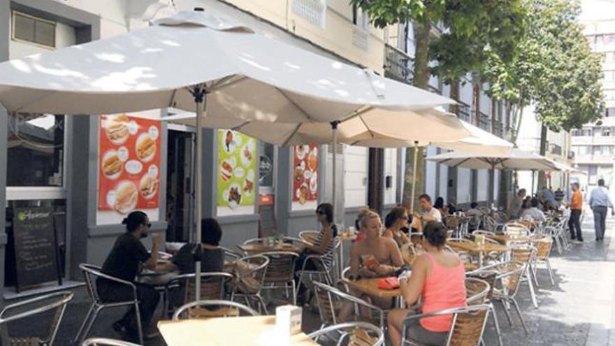 Varios clientes disfrutan del verano en una de las terrazas de los bares que se encuentran en los alrededores de la comercial calle Triana. | j. c. castro