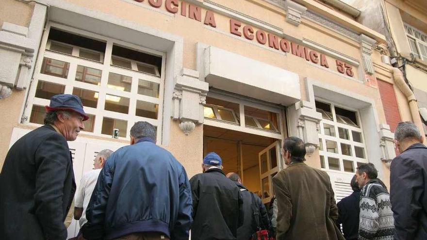 Un grupo de personas espera para entrar a comer en la Cocina Económica.