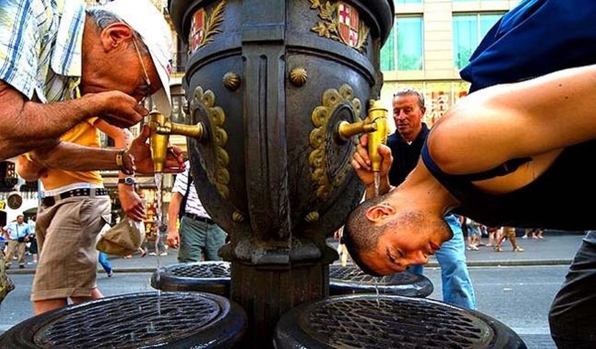 Un turista es refresca a la font de Canaletes en un intent d’evitar l’onada de calor.