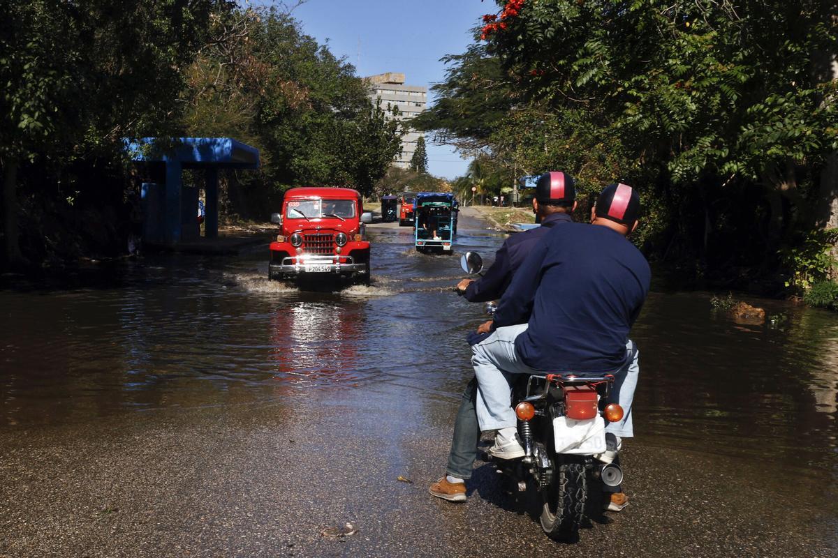 AME4081. LA HABANA (CUBA), 11/02/2026.- Personas transitan en vehículos por una calle inundada este miércoles, en La Habana (Cuba). El peso cubano marcó un mínimo histórico en el mercado informal al depreciarse hasta las 500 unidades por dólar estadounidense, en medio de las crecientes presiones de Washington sobre la isla. EFE/ Ernesto Mastrascusa