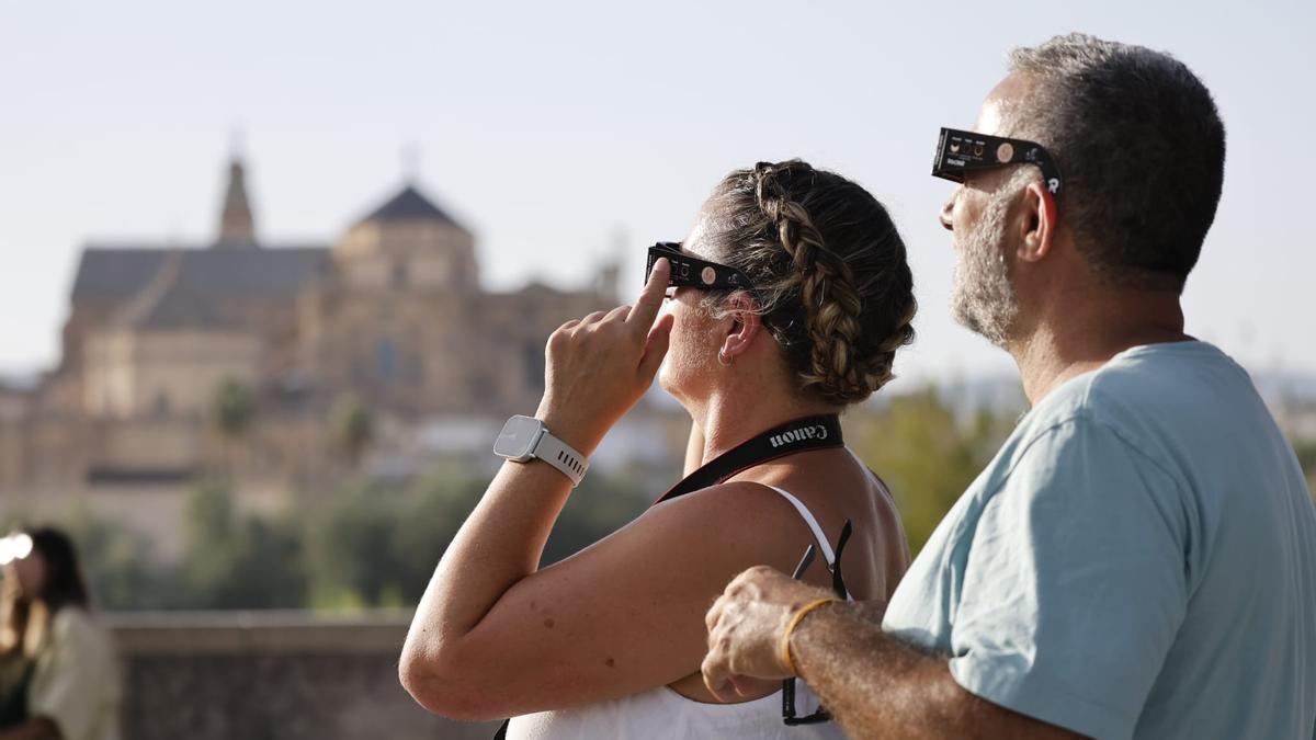 Dos personas esperan el eclipse en el entorno del Puente Romano de Córdoba.