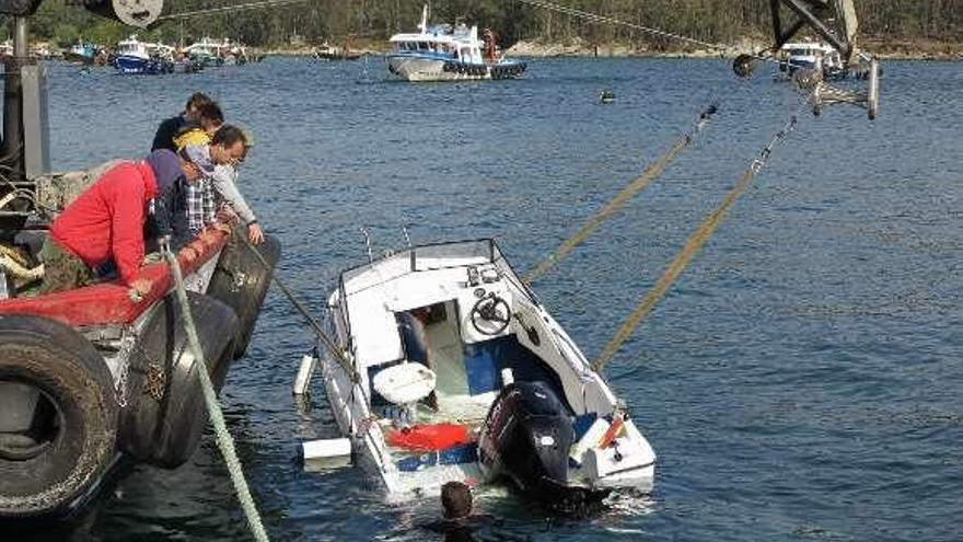 La grúa de un bateeiro reflota la lancha volcada. // Muñiz