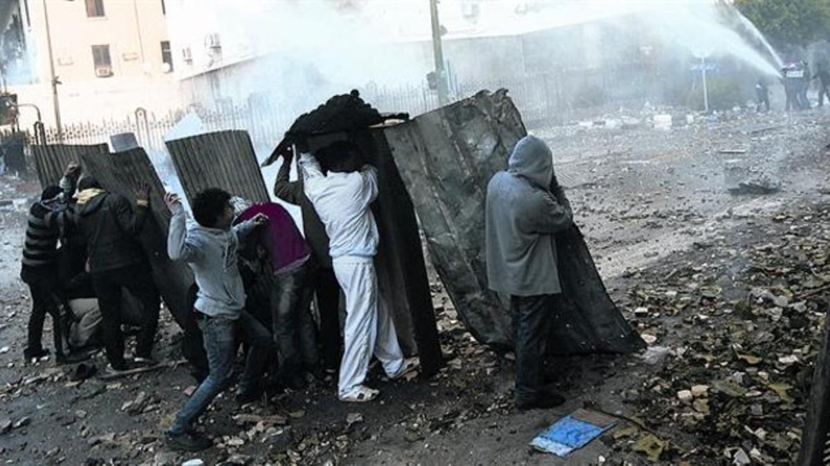 Manifestantes lanzan piedras contra los soldados cerca de la plaza de Tahrir, ayer, en El Cairo.