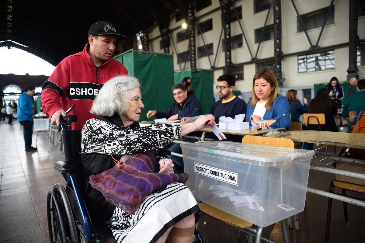 Una mujer mayor deposita su voto en una urna durante el referendum constitucional de Chile.