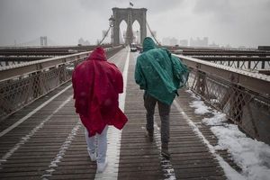 Dos turistes travessen el pont de Brooklyn enmig d’una tempesta de neu a Nova York, avui, dilluns 26 de gener del 2015. Més de dos mil vols han estat cancel·lats avui a la ciutat i al nord-est del país a causa del temporal de neu que afectarà amb força en les pròximes hores la regió, segons informes de les companyies aèries.