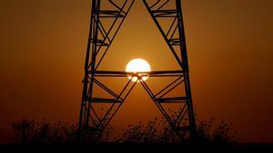 Una torre de electricidad con el sol de fondo.