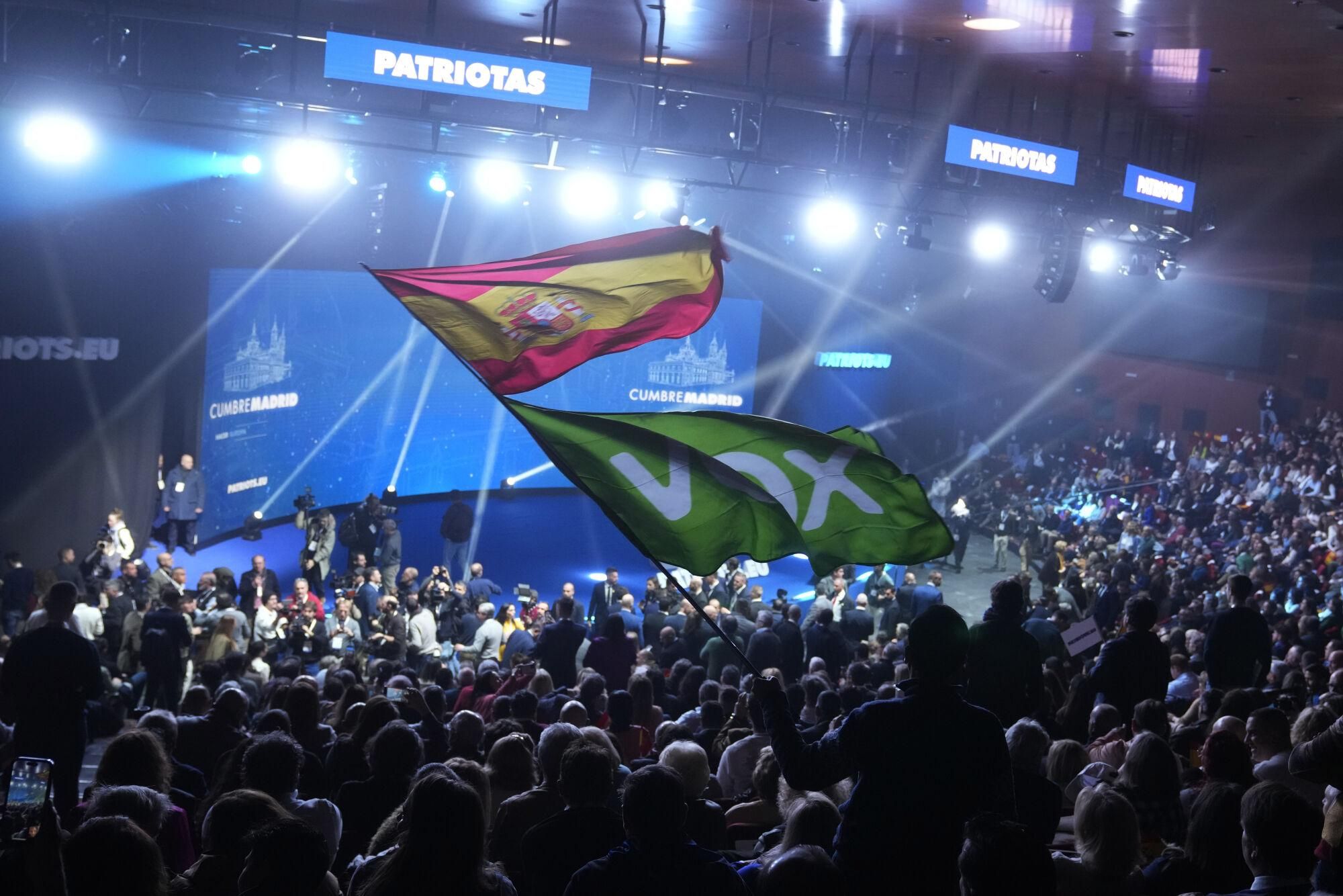 A Spanish flag and a Spanish far-right VOX party flag are waved during the far-right Patriots for Europe summit in Madrid, Spain, Saturday, Feb. 8, 2025. (AP Photo/Paul White)