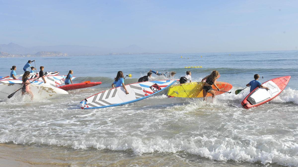 Un grupo de menores  entra en el agua con  sus tablas en la playa de  Arenales del Sol.