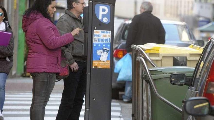 Una mujer abona la tarifa de la ORA en un parquímetro.