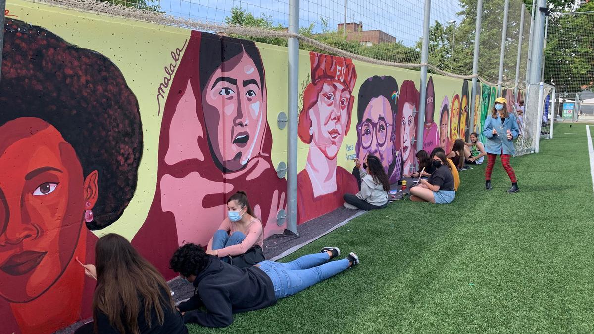 Varios alumnos del Institut Josep Mestres i Busquets pintan un mural con reivindicación feminista en el campo de fútbol