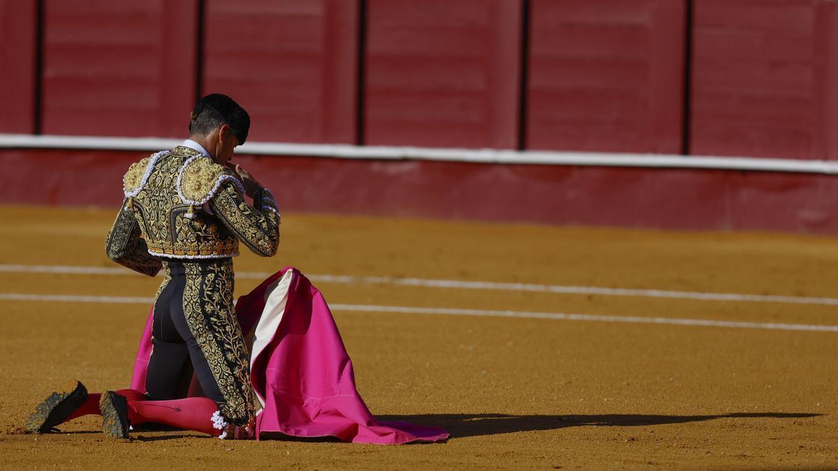 El diestro Manuel Escribano espera de rodillas a su primer toro durante el festejo correspondiente a la Feria de Málaga.