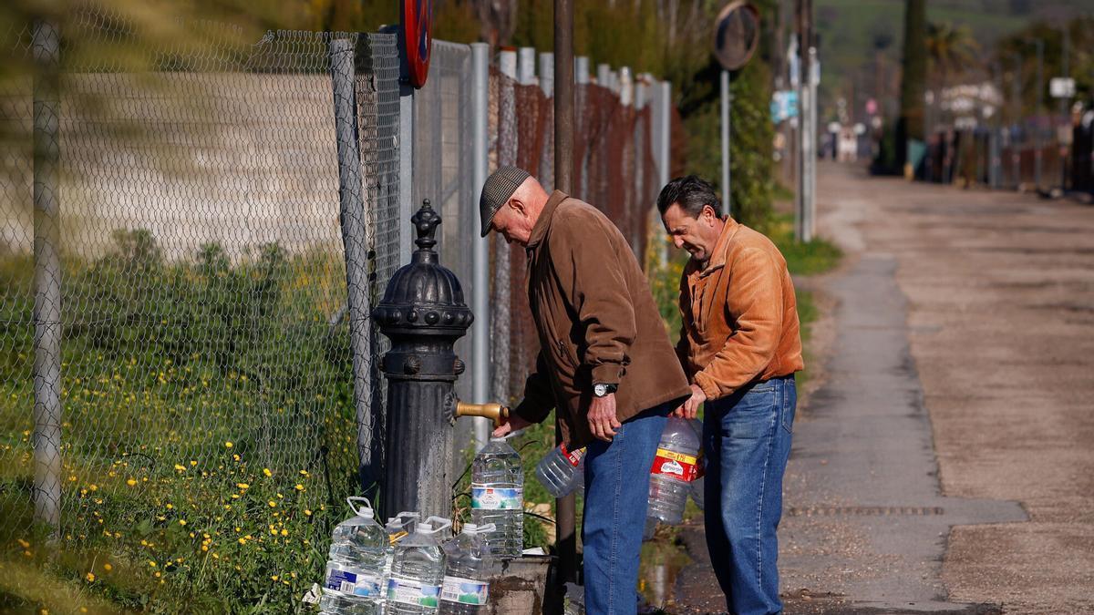 Dos vecinos llenan garrafas de agua en una fuente pública situada en la parcelación de Cuevas de Altázar.