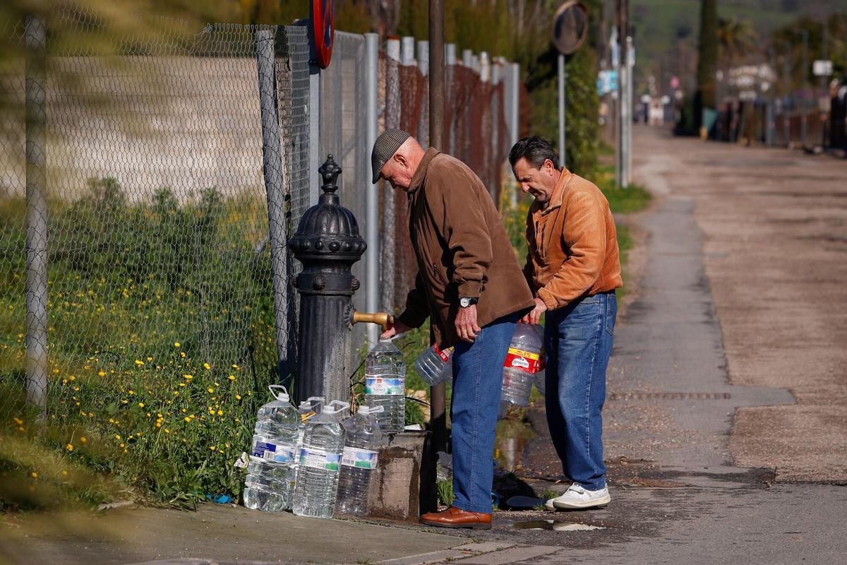 Dos vecinos llenan garrafas de agua en una fuente pública situada en la parcelación de Cuevas de Altázar.