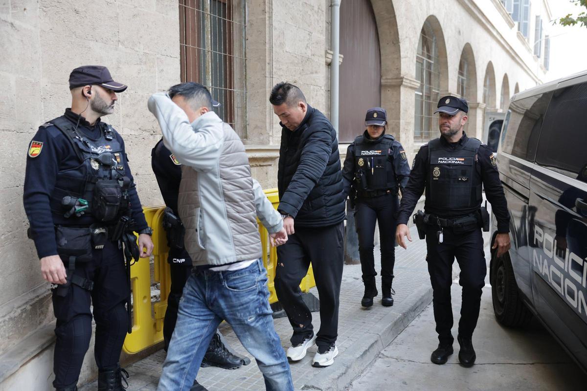 Detenidos de la supuesta red de explotación de mujeres chinas se cubren el rostro al pasar al juzgado.