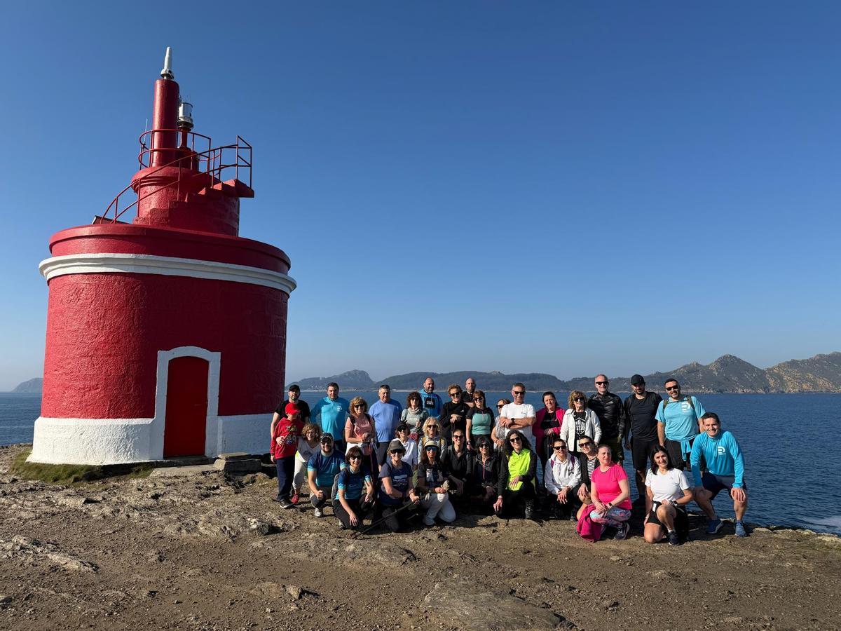 Los participantes en la ruta de este domingo posan al lado del faro de Robaleira, en la Costa da Soavela, y con las Cíes al fondo.