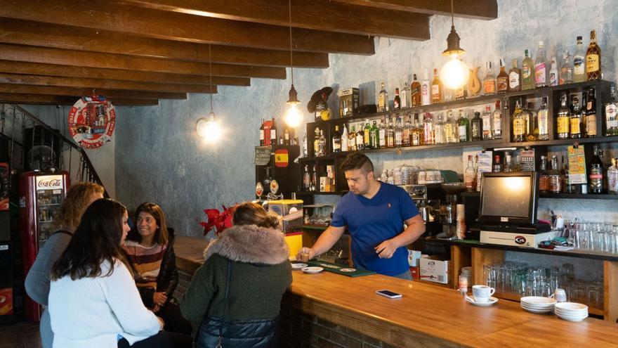 Un camarero atiende en la barra a un grupo de personas.