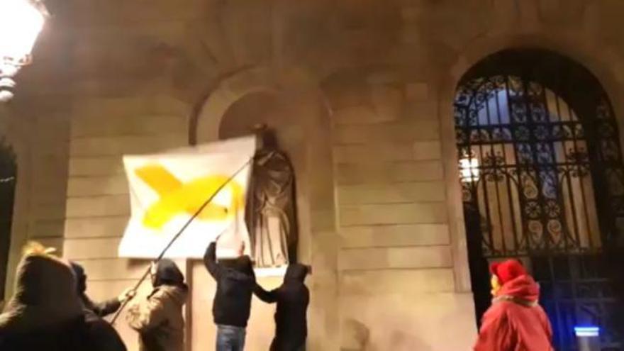 Un grup de persones arrenca la pancarta amb el llaç groc de l'ajuntament de Barcelona