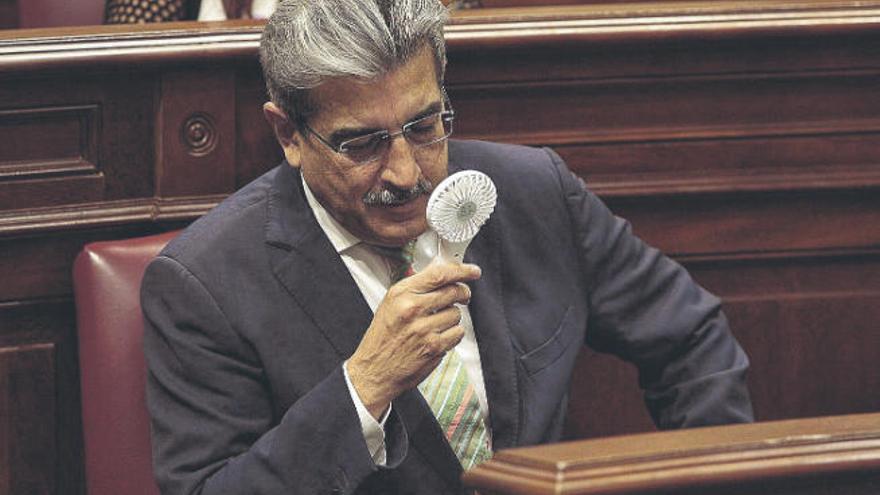 Román Rodríguez, consejero de Hacienda, se refresca con un miniventilador portátil en el Parlamento.