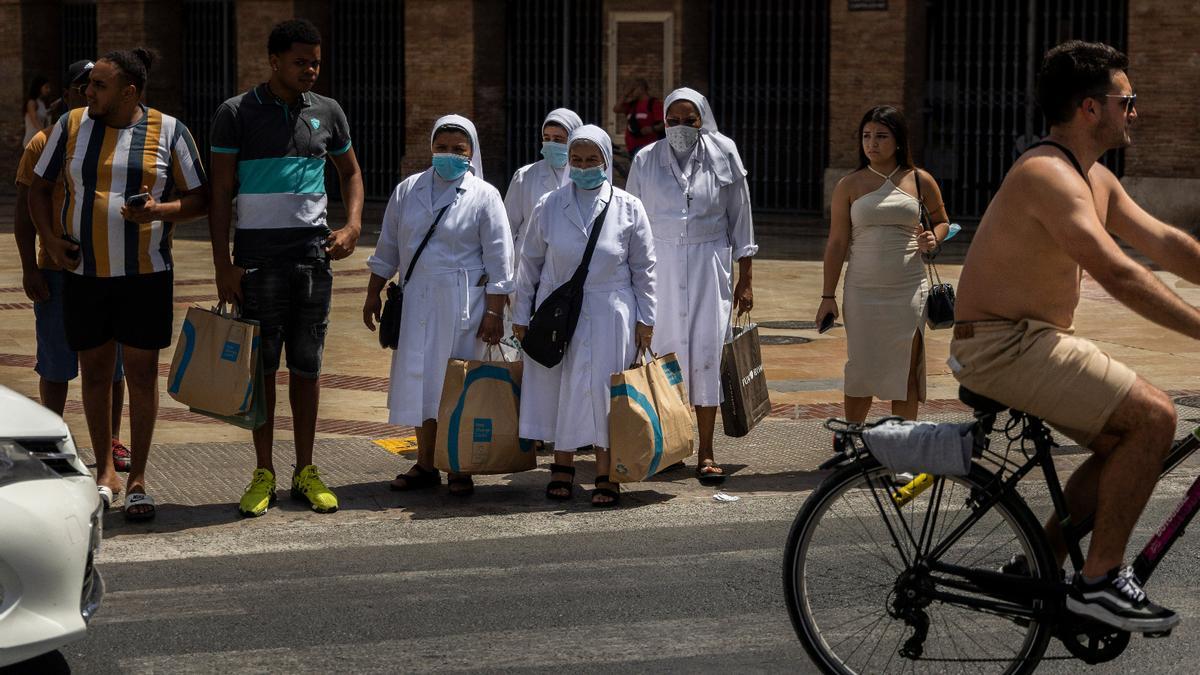 Un grupo de religiosas con bolsas de Primark esperan a cruzar la calle Xàtiva ataviadas de blanco en plena ola de calor.