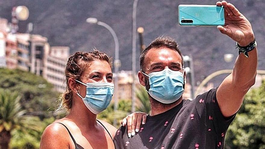 Una pareja con mascarilla en la Plaza de España de la capital.