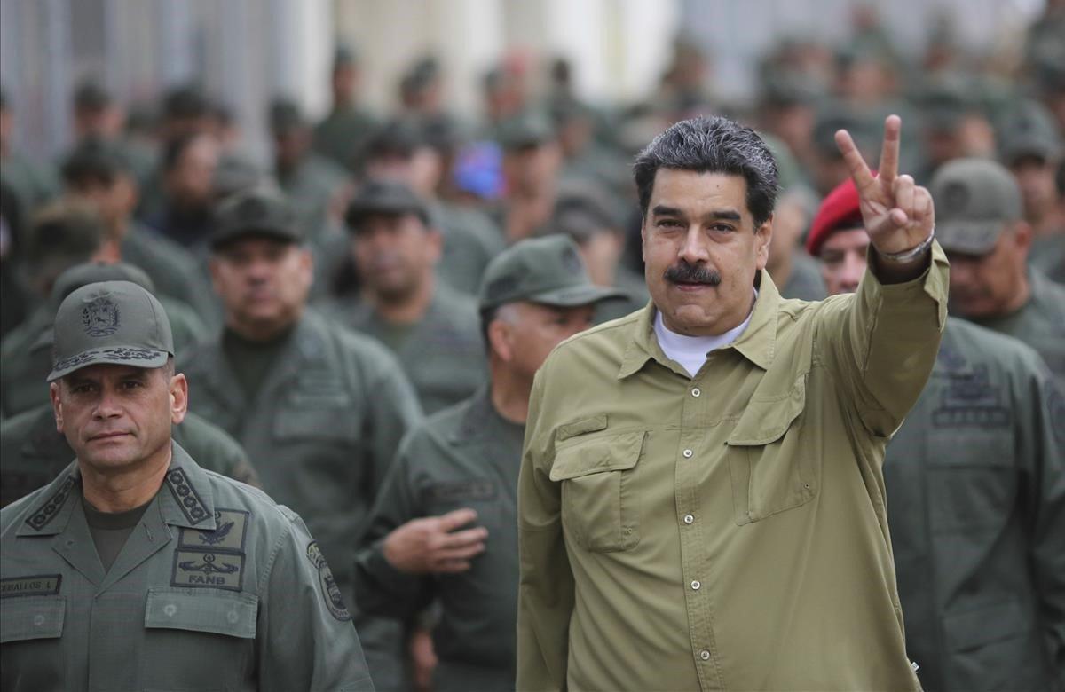 En esta foto publicada por la Oficina de Prensa de la Presidencia de Miraflores, el presidente de Venezuela, Nicolás Maduro, hace un gesto con la mano de V de victoria después de llegar a la base militar de Fort Tiuna en Caracas, Venezuela.