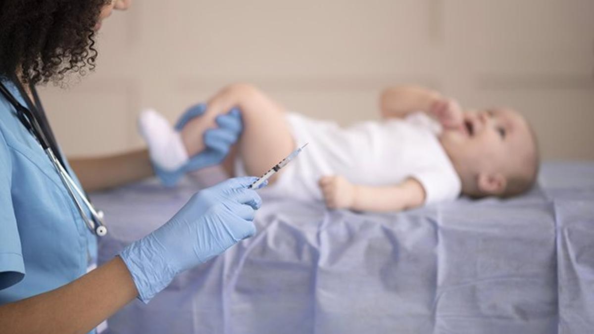 Una enfermera se prepara para vacunar a un bebé.