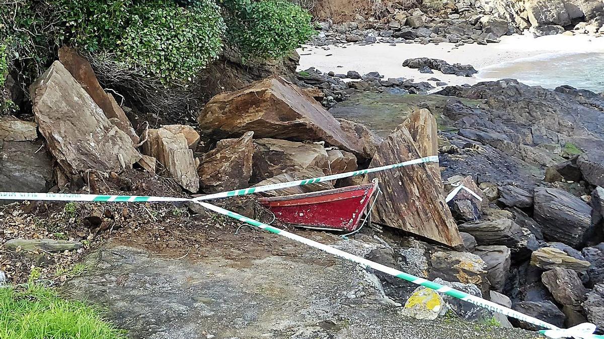Una barca aplastada por las rocas tras otro desprendimiento en O Xunqueiro, que cerró el paso a la cala. |  // I. R.
