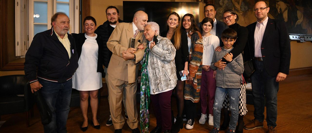 Sánchez de Dios besa a su esposa, Amalia Lloria, rodeados de su familia, tras el homenaje y con el galardón en sus manos