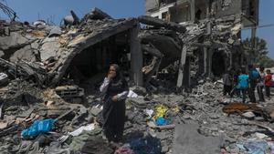 Familias palestinas inspeccionan sus casas destruidas en el campo de refugiados de Al Maghazi, en el centro de la Franja de Gaza.