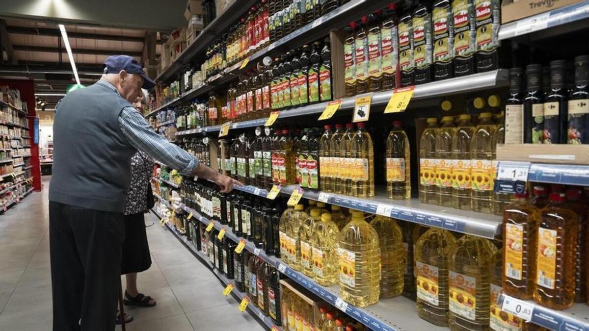 Una pareja compra aceite en un supermercado.
