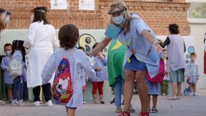 Una profesora saluda a sus alumnos en el primer día de colegio.