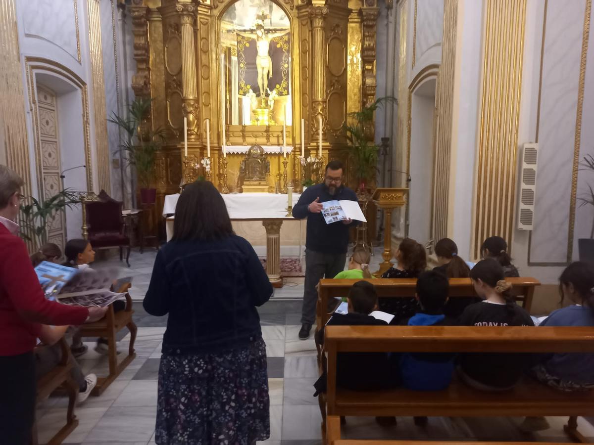 El párroco explica a los niños el álbum de cromos de la Semana Santa.