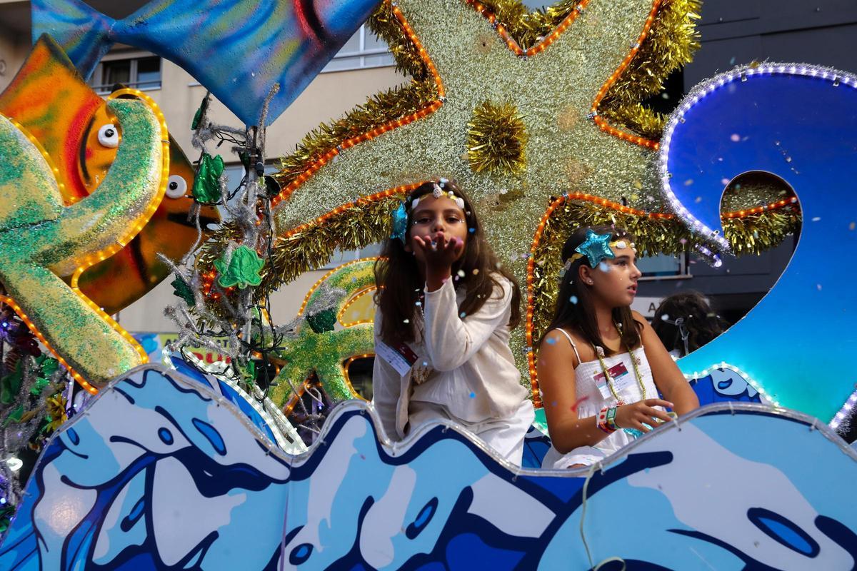 Una niña sopla para hacer volar el confeti que lleva en la mano.