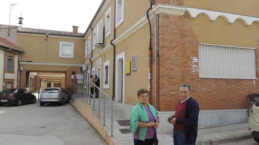 Dos personas junto al edificio en cuyo bajo se encuentra el velatorio.