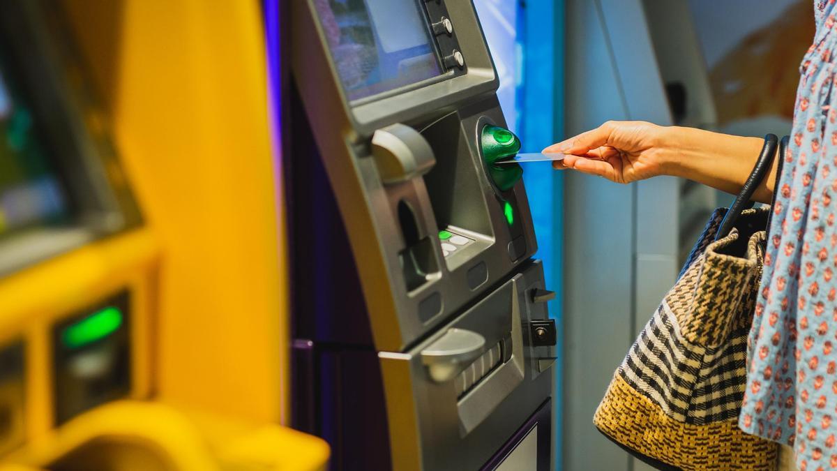 Una mujer sacando dinero de un cajero.