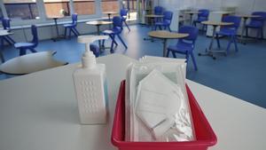Mascarillas KN-95 y gel desinfectante en la mesa del profesor de un aula de Madrid.