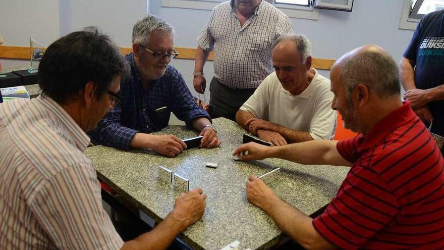 El alcalde, Xose M. Pazos, y el edil de Deportes, Xoán Chillón, juegan una partida de dominó con los miembros de la organización durante la presentación de ayer. // G. Núñez