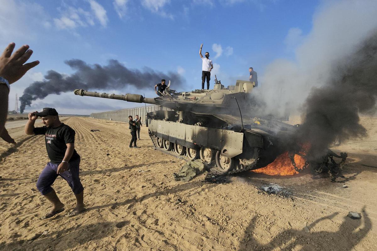 Los palestinos celebran junto a un tanque israelí destruido en la valla de la Franja de Gaza al este de Khan Younis, en el sur, el sábado.