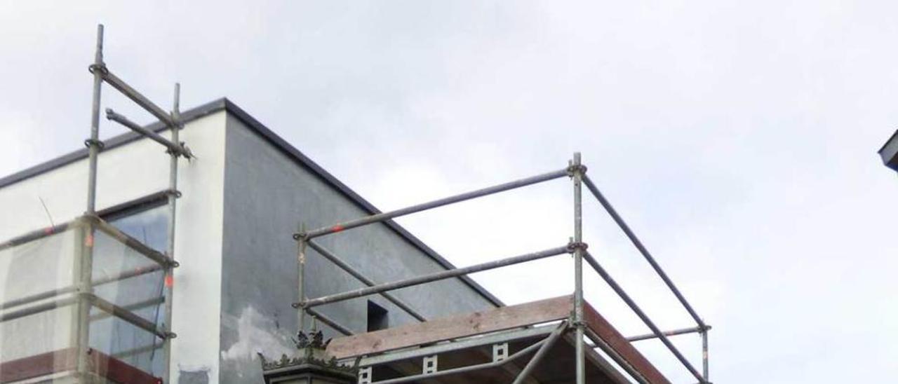 Los operarios, pintando la fachada de la residencia de Santolaya de Cabranes de blanco roto.