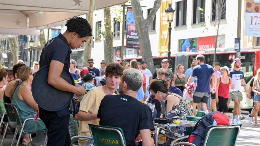 Un camarero cobra a unos clientes en la terraza de un negocio de hostelería.